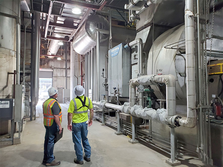 Two men standing near boiler system